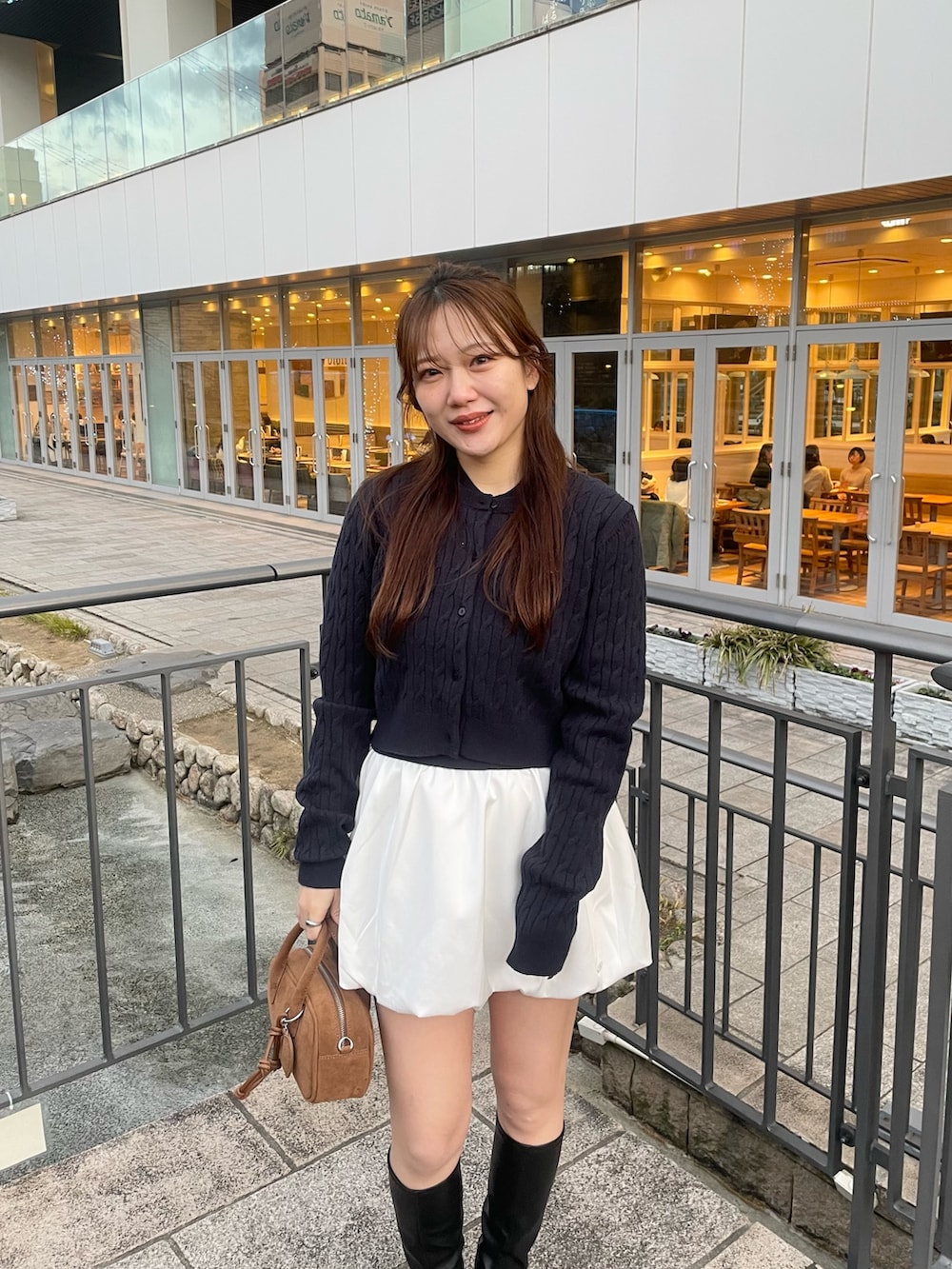 ブルー系のカーディガン/ボレロ、ホワイト系のスカート、ベージュ系のボストンバッグを着用したレディースの春コーディネートの2枚目の写真