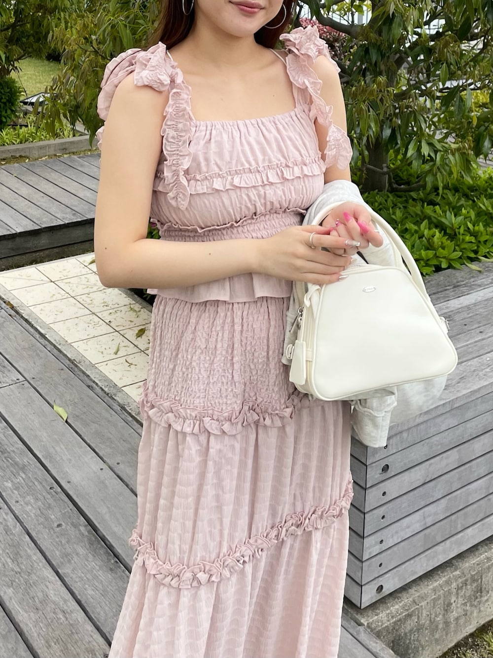 ピンク系のワンピース、ベージュ系のパーカー、ホワイト系のボストンバッグを着用したレディースの春コーディネートの3枚目の写真