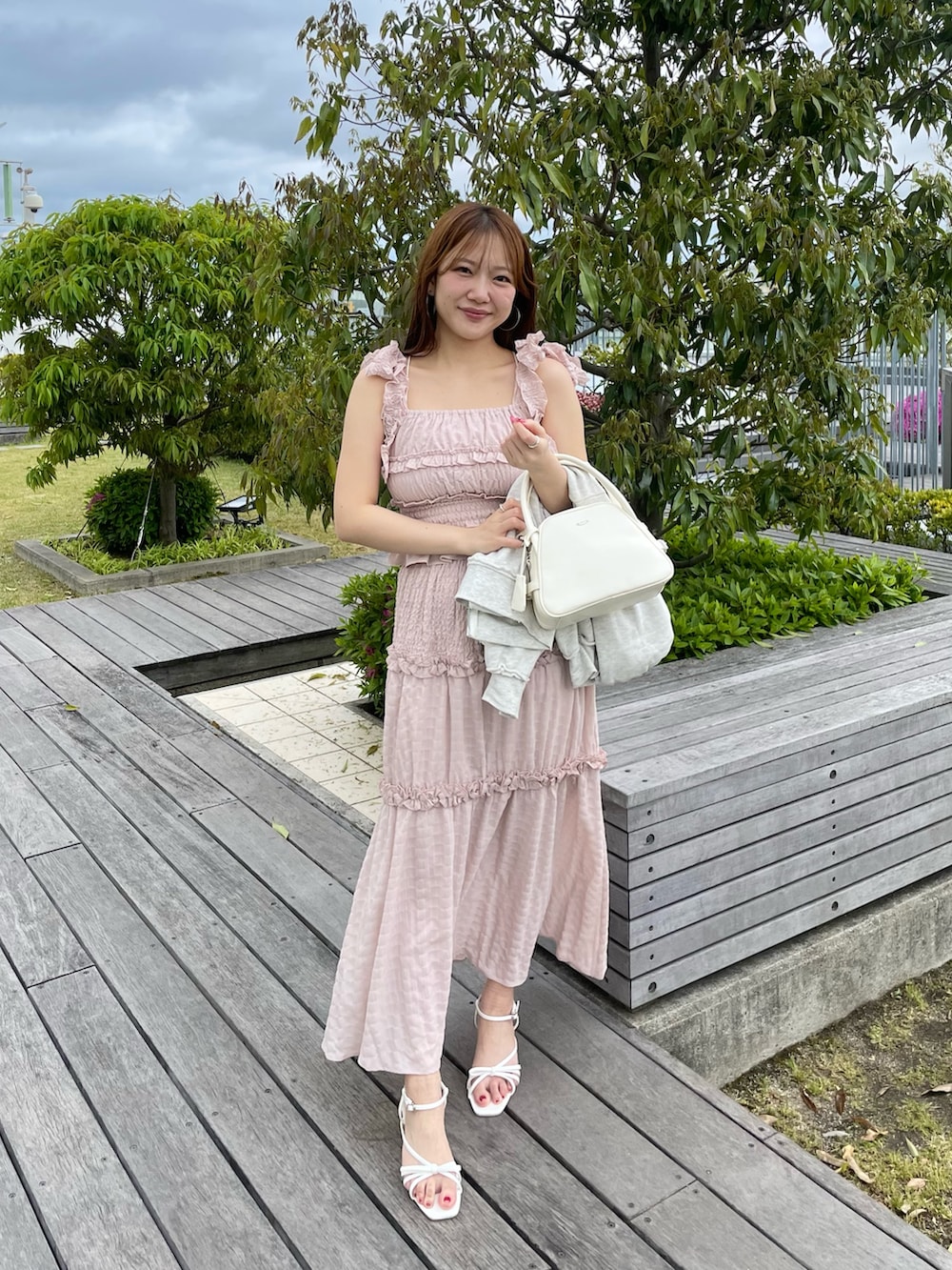 ピンク系のワンピース、ベージュ系のパーカー、ホワイト系のボストンバッグを着用したレディースの春コーディネートの4枚目の写真