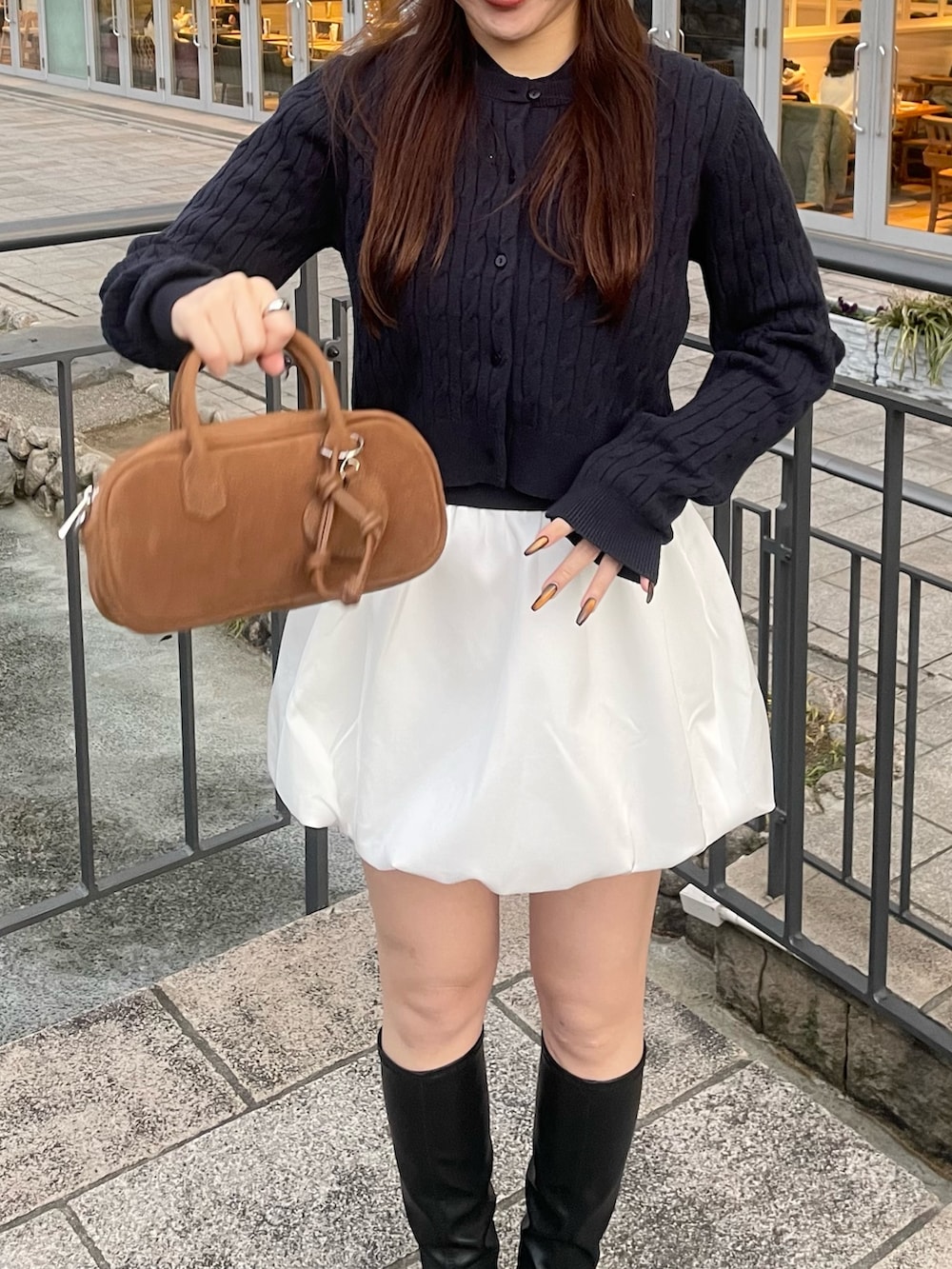 ブルー系のカーディガン/ボレロ、ホワイト系のスカート、ベージュ系のボストンバッグを着用したレディースの春コーディネートの4枚目の写真