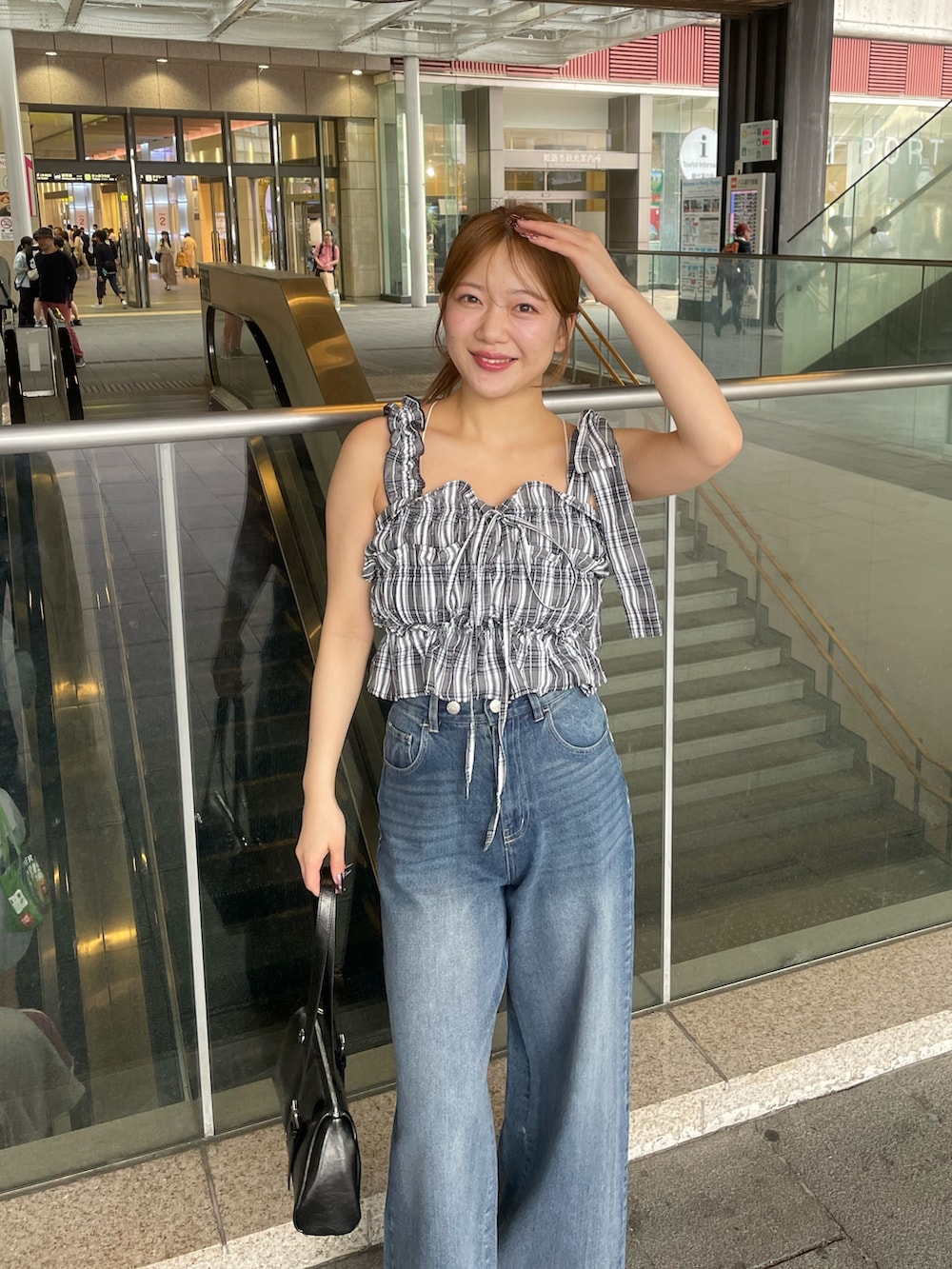 ブラック系のワンピース、ブルー系のデニムパンツ、ブラック系のボストンバッグを着用したレディースの春コーディネートの3枚目の写真