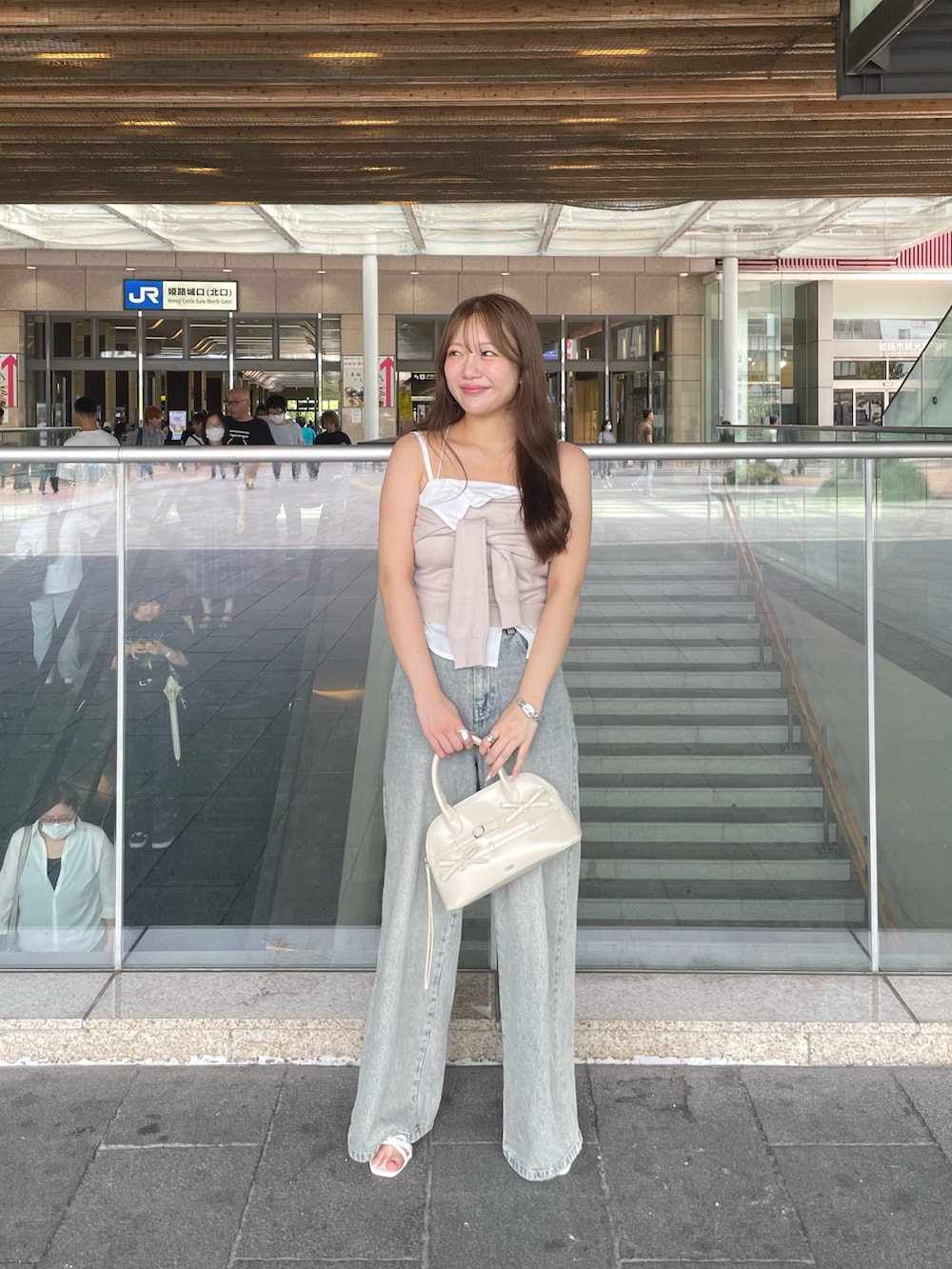 ベージュ系のキャミソール、ブルー系のデニムパンツ、ホワイト系のボストンバッグを着用したレディースの夏コーディネートの4枚目の写真