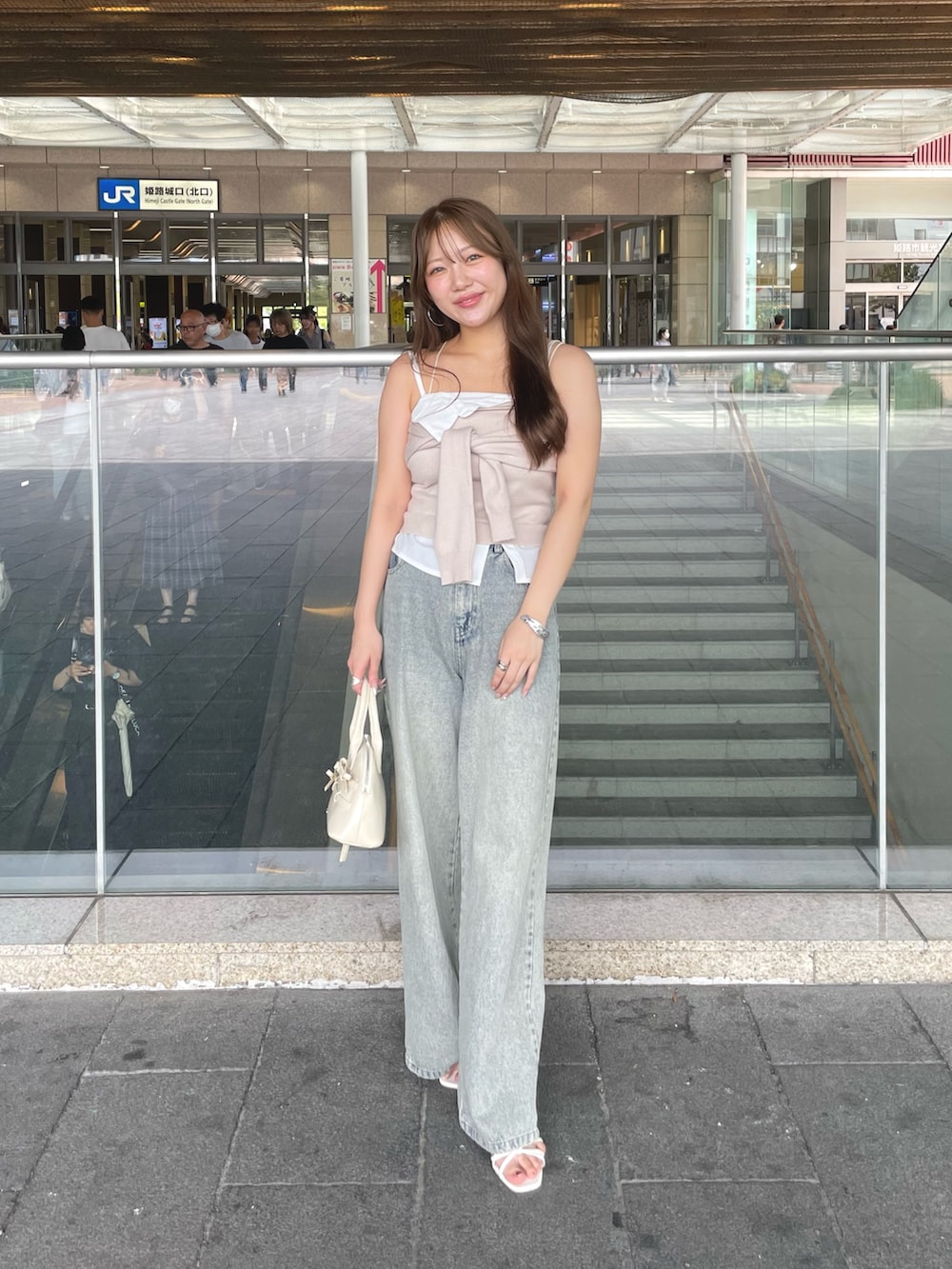 ベージュ系のキャミソール、ブルー系のデニムパンツ、ホワイト系のボストンバッグを着用したレディースの夏コーディネートの3枚目の写真