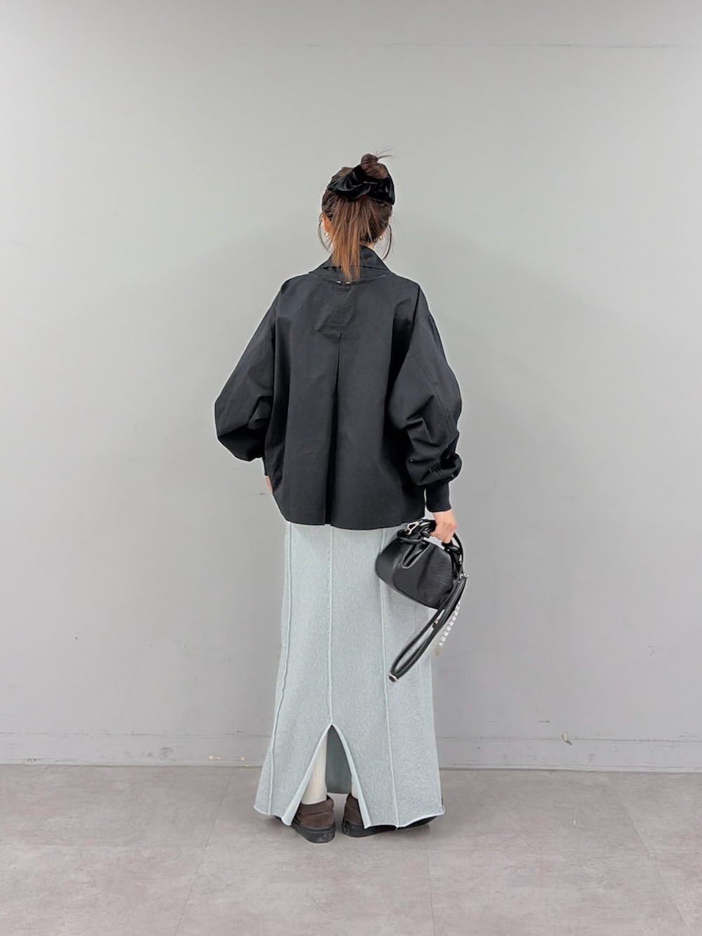 ブルー系のスカート、ブラック系のショルダーバッグ、ブラック系のトレンチコートを着用したレディースの冬コーディネートの3枚目の写真