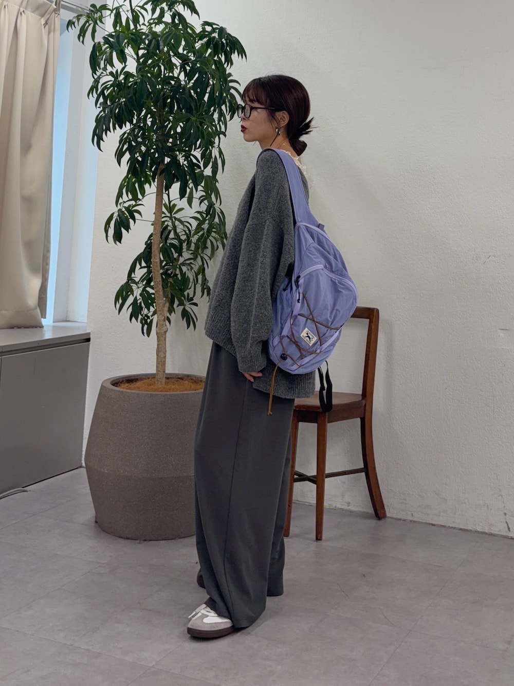 グレー系のニット/セーター、パープル系のバックパック/リュック、グレー系のスラックスを着用したレディースの秋コーディネートの2枚目の写真