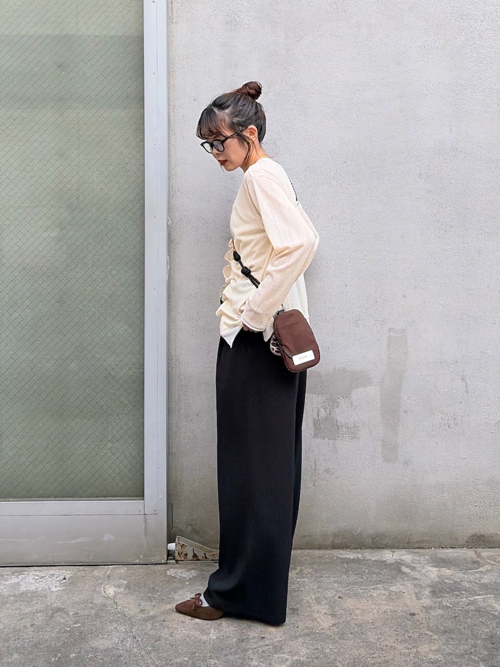 イエロー系のTシャツ/カットソー、ブラック系のスラックスを着用したレディースの冬コーディネートの2枚目の写真