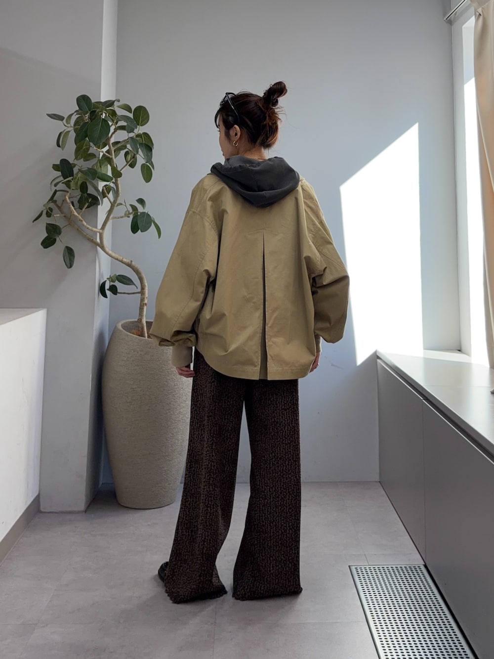 ベージュ系のトレンチコート、グレー系のパーカー、ブラウン系のその他パンツを着用したレディースの冬コーディネートの3枚目の写真