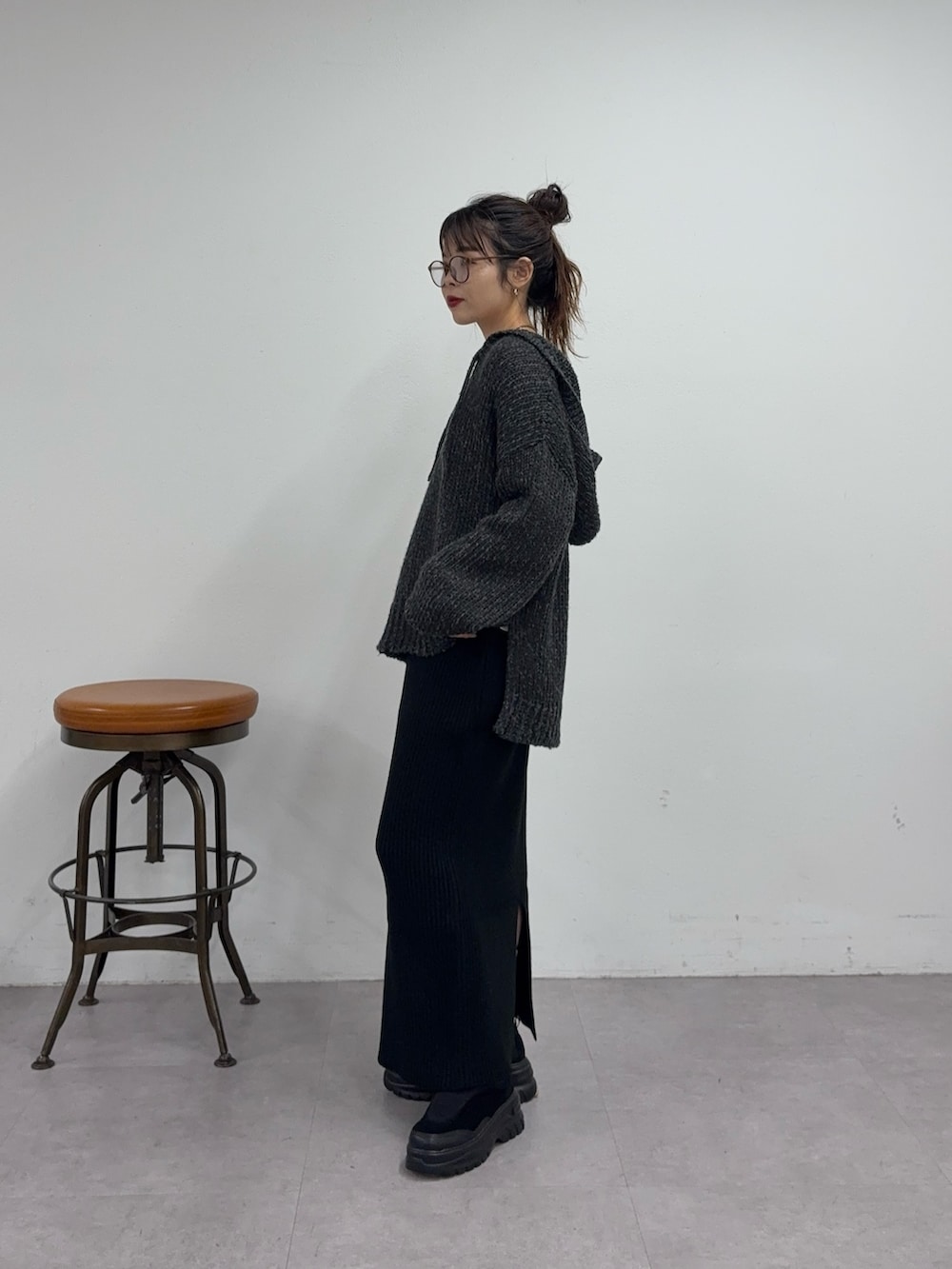 ブラック系のスカート、ブラック系のスニーカー、グレー系のニット/セーターを着用したレディースの秋コーディネートの2枚目の写真