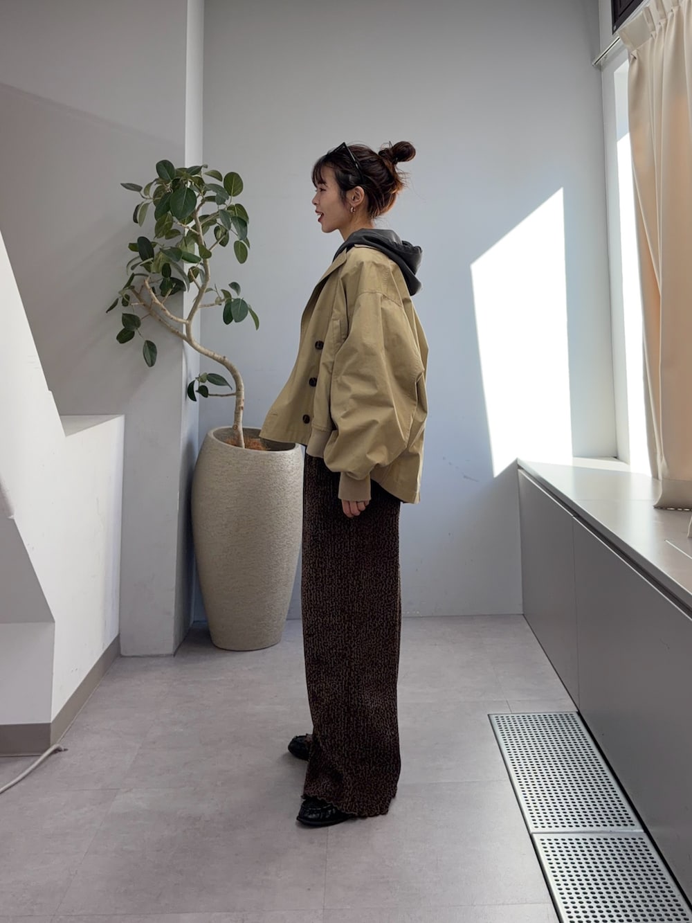 ベージュ系のトレンチコート、グレー系のパーカー、ブラウン系のその他パンツを着用したレディースの冬コーディネートの2枚目の写真