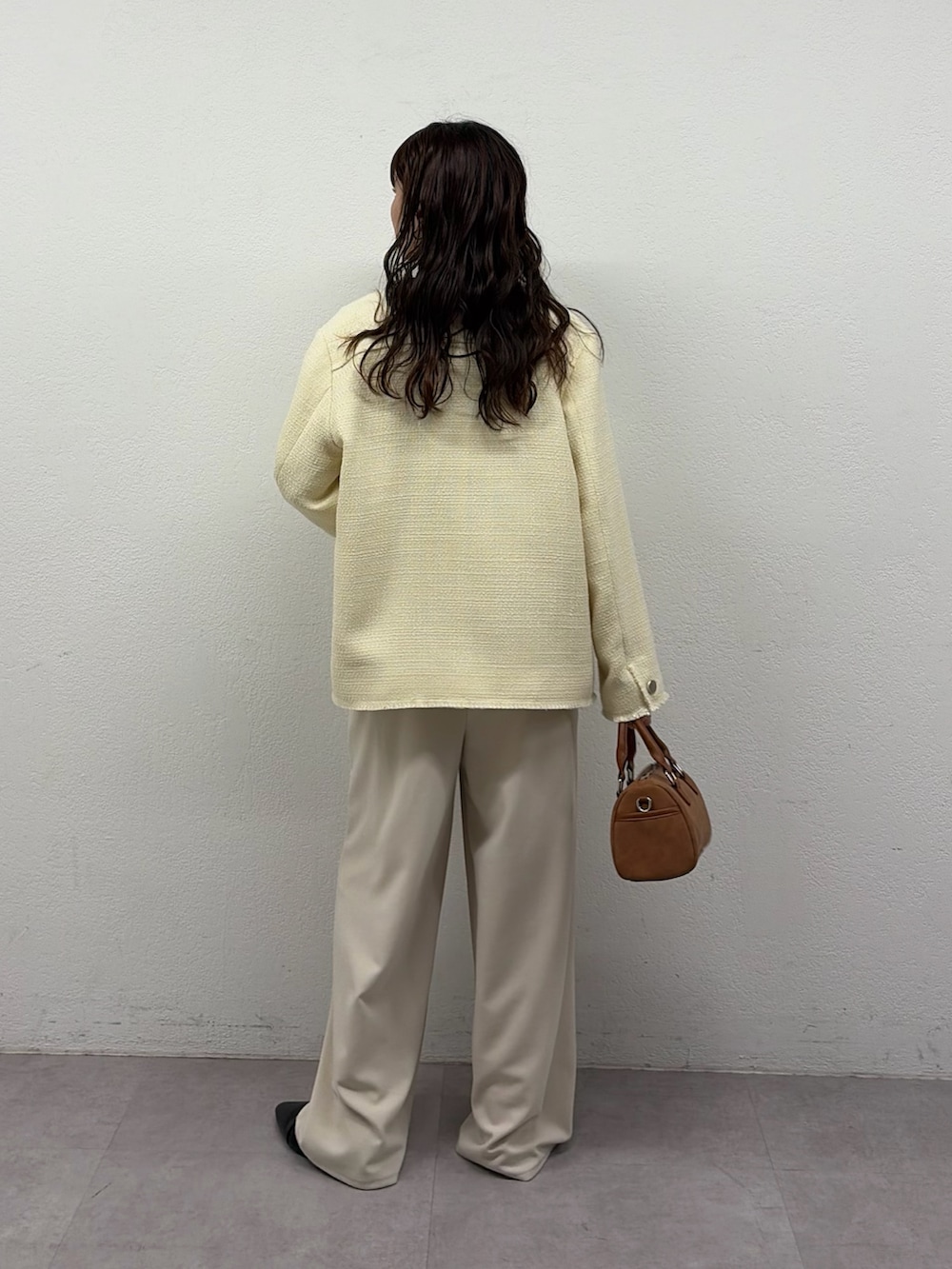 イエロー系のテーラードジャケット、ベージュ系のサロペット/オーバーオール、ブラック系のパンプスを着用したレディースの冬コーディネートの3枚目の写真