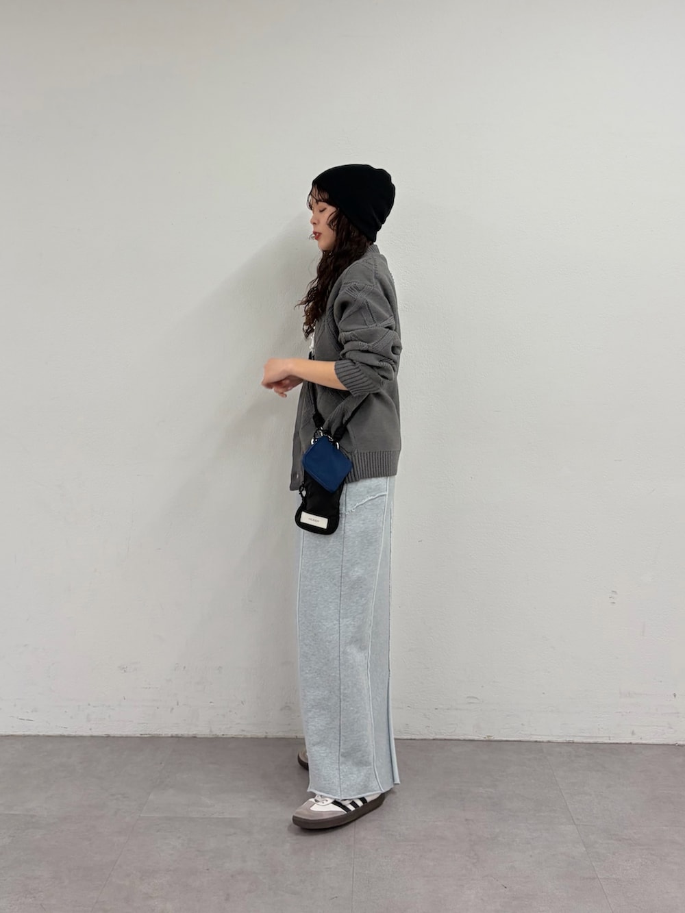 グレー系のカーディガン/ボレロ、ブルー系のスカート、ブラック系のショルダーバッグを着用したレディースの春コーディネートの2枚目の写真