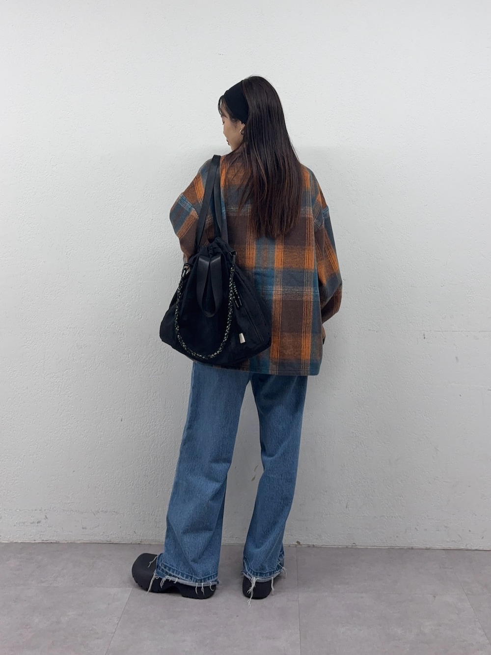 オレンジ系のシャツ/ブラウス、ブルー系のデニムパンツ、ブラック系のトートバッグを着用したレディースの秋コーディネートの2枚目の写真