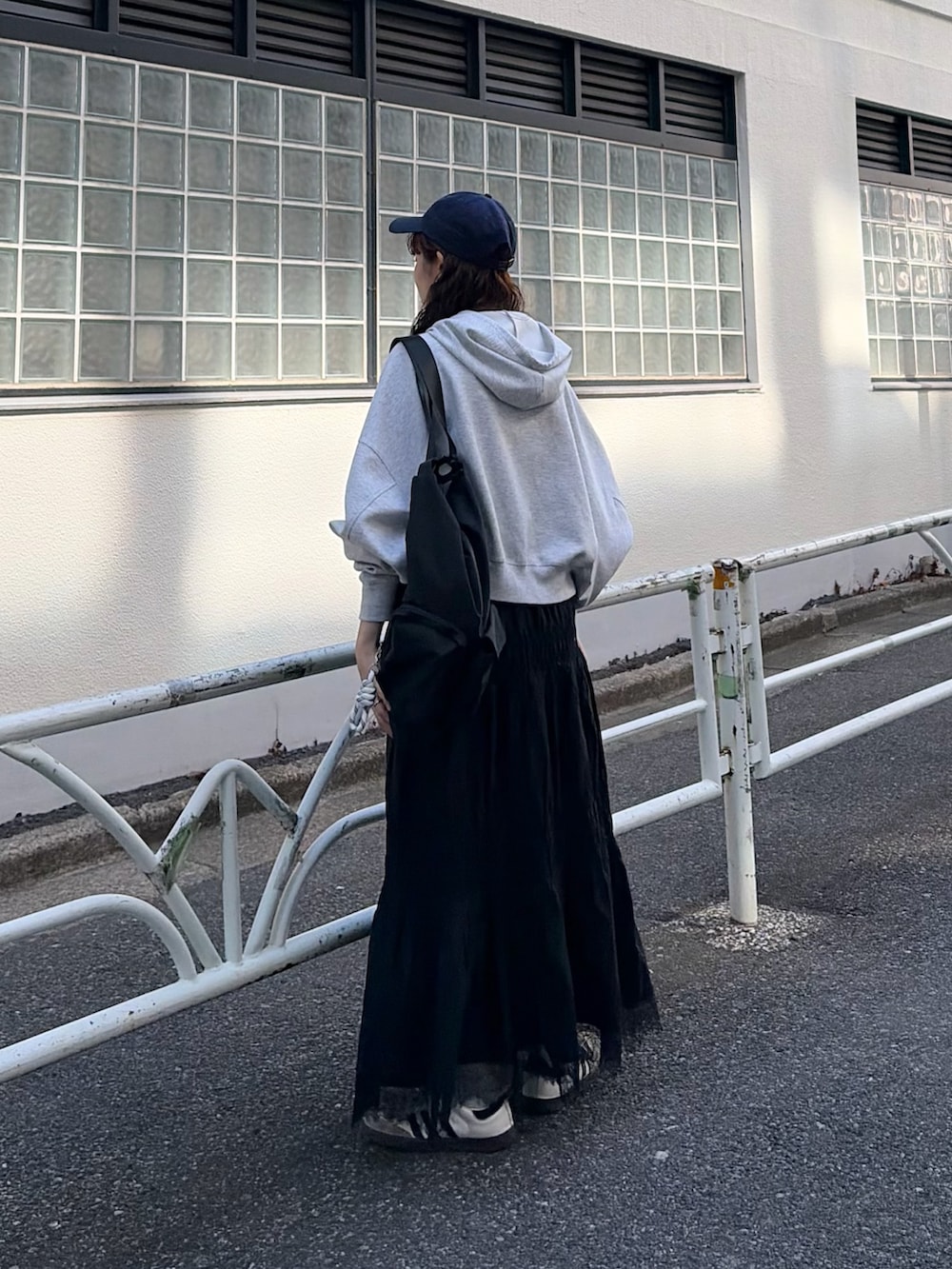 グレー系のパーカー、ホワイト系のスカートを着用したレディースの春コーディネートの2枚目の写真