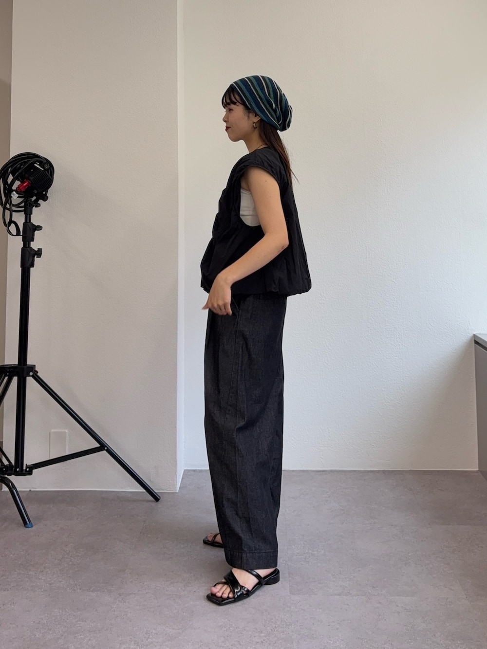 ブラック系のベスト、ブラック系のデニムパンツ、ブラック系のサンダルを着用したレディースの夏コーディネートの2枚目の写真