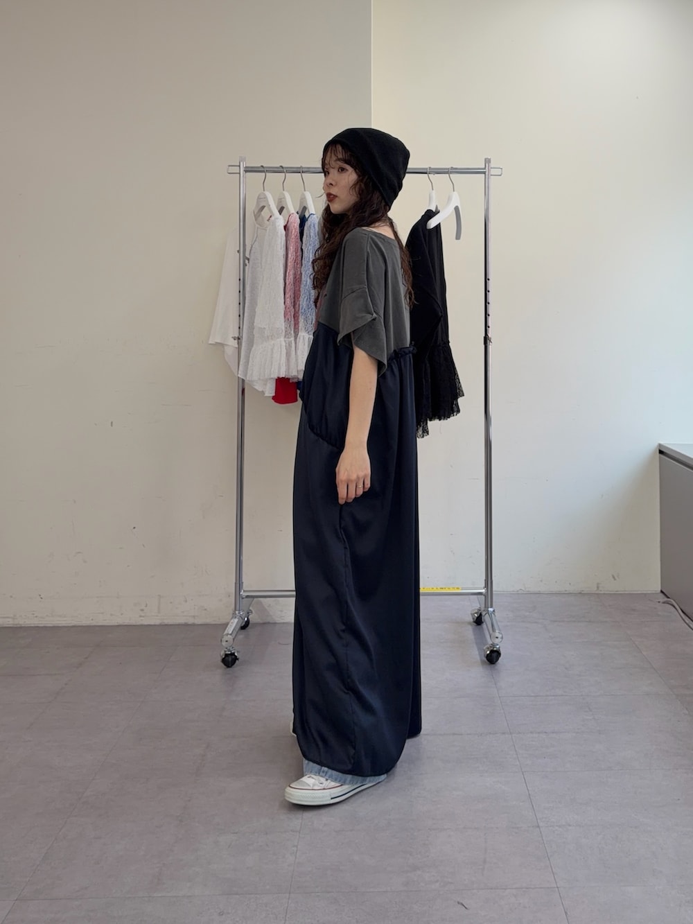 グレー系のワンピース、ブルー系のデニムパンツ、ブラック系のニットキャップ/ビーニーを着用したレディースの春コーディネートの2枚目の写真