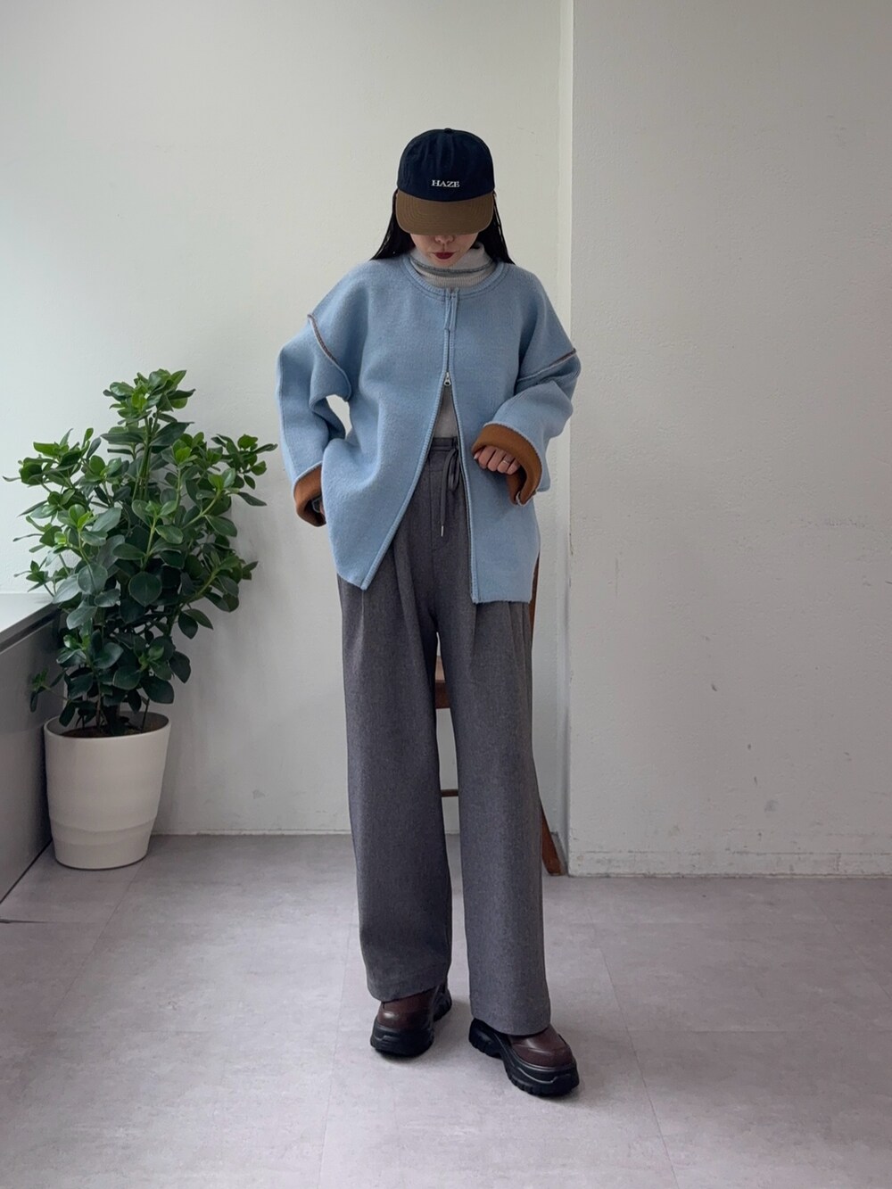 グレー系のニット/セーター、ブルー系のカーディガン/ボレロ、グレー系のスラックスを着用したレディースの秋コーディネートの2枚目の写真