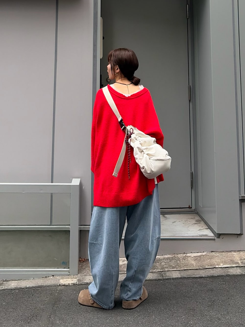 レッド系のニット/セーター、ブルー系のデニムパンツを着用したレディースの秋コーディネートの2枚目の写真