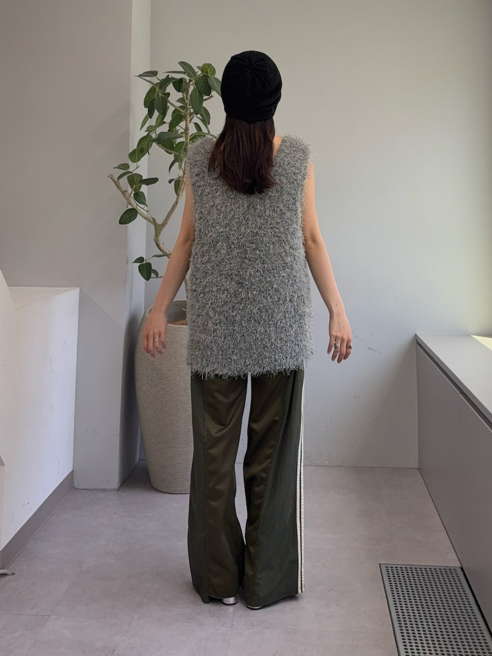 グレー系のベスト、グリーン系のスウェットパンツ、シルバー系のパンプスを着用したレディースの春コーディネートの3枚目の写真