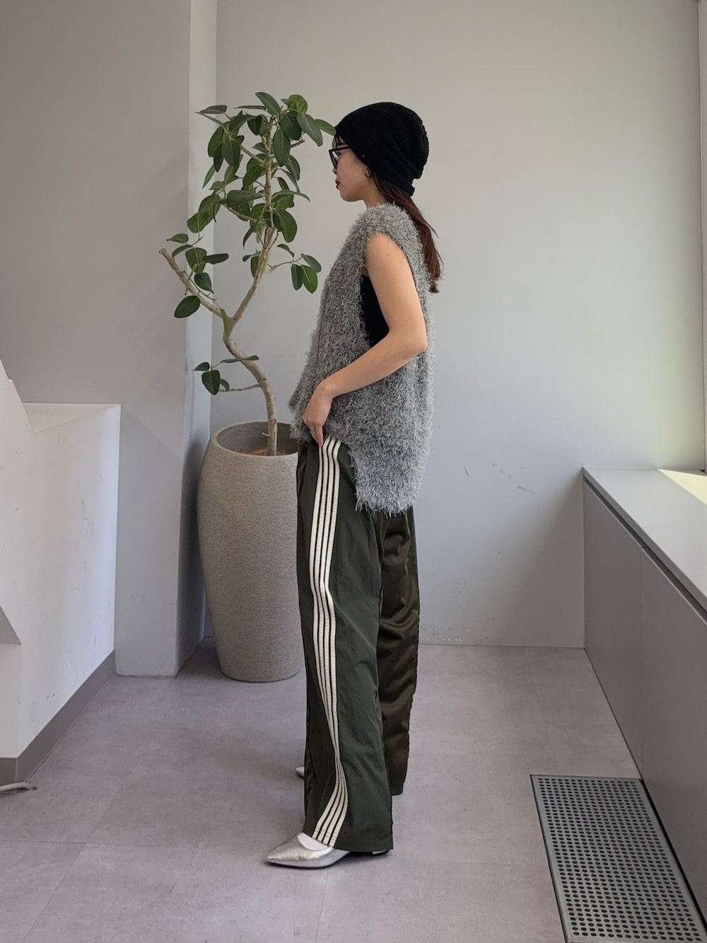 グレー系のベスト、グリーン系のスウェットパンツ、シルバー系のパンプスを着用したレディースの春コーディネートの2枚目の写真