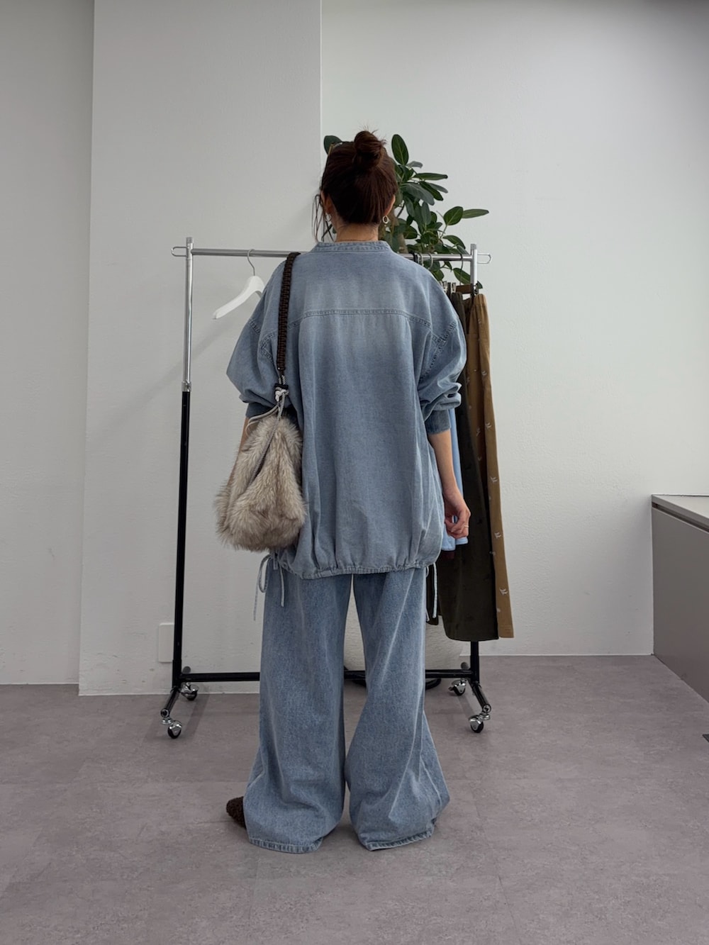 ブルー系のデニムパンツ、ベージュ系のトートバッグ、ブルー系のシャツ/ブラウスを着用したレディースの秋コーディネートの3枚目の写真