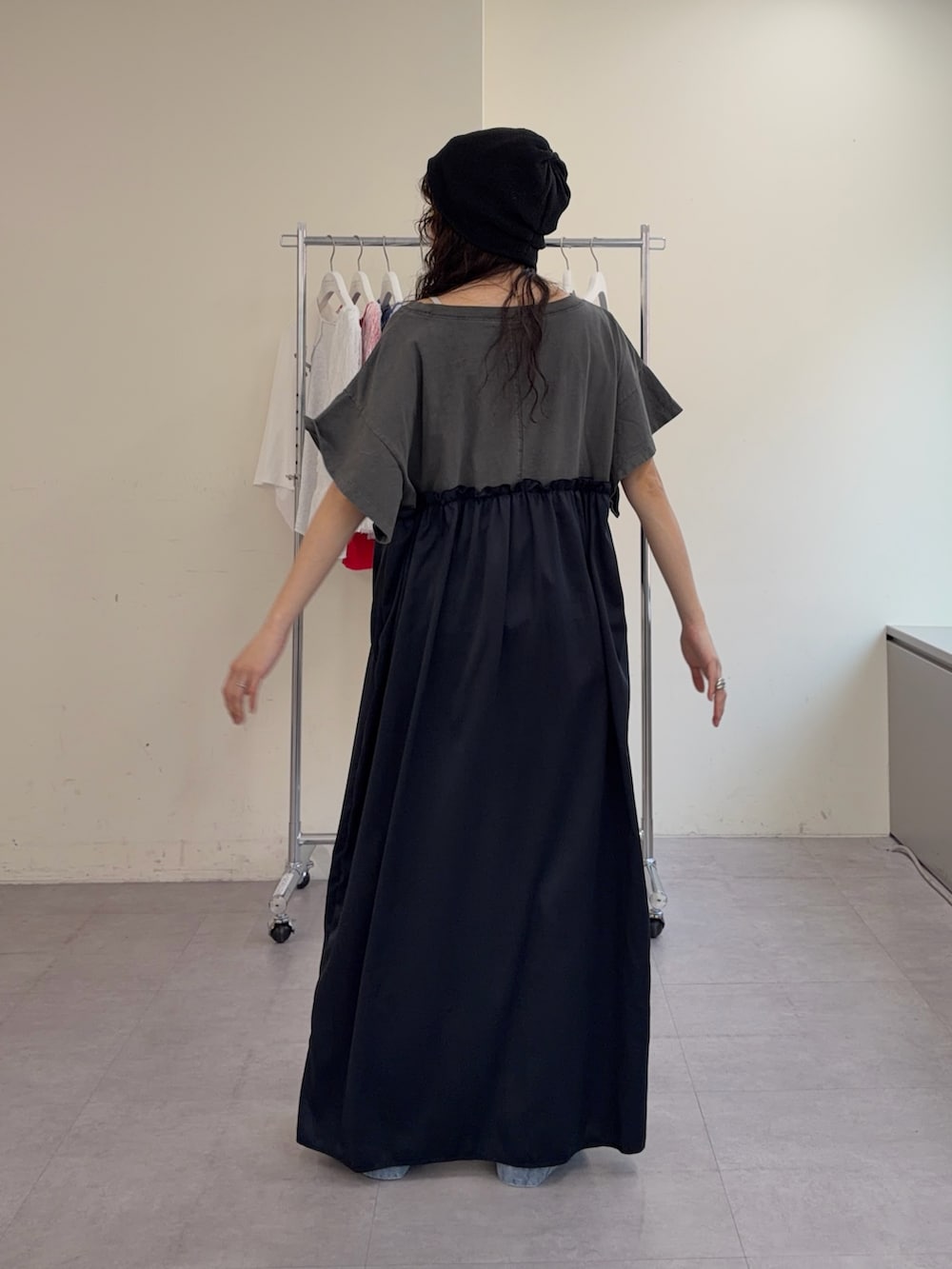 グレー系のワンピース、ブルー系のデニムパンツ、ブラック系のニットキャップ/ビーニーを着用したレディースの春コーディネートの3枚目の写真