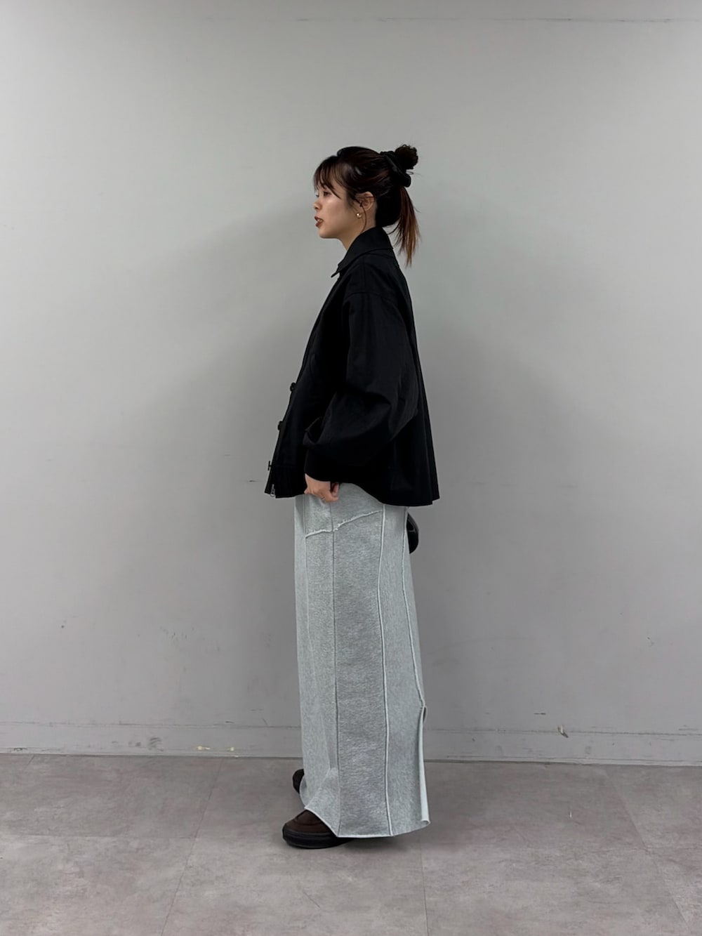 ブルー系のスカート、ブラック系のショルダーバッグ、ブラック系のトレンチコートを着用したレディースの冬コーディネートの2枚目の写真