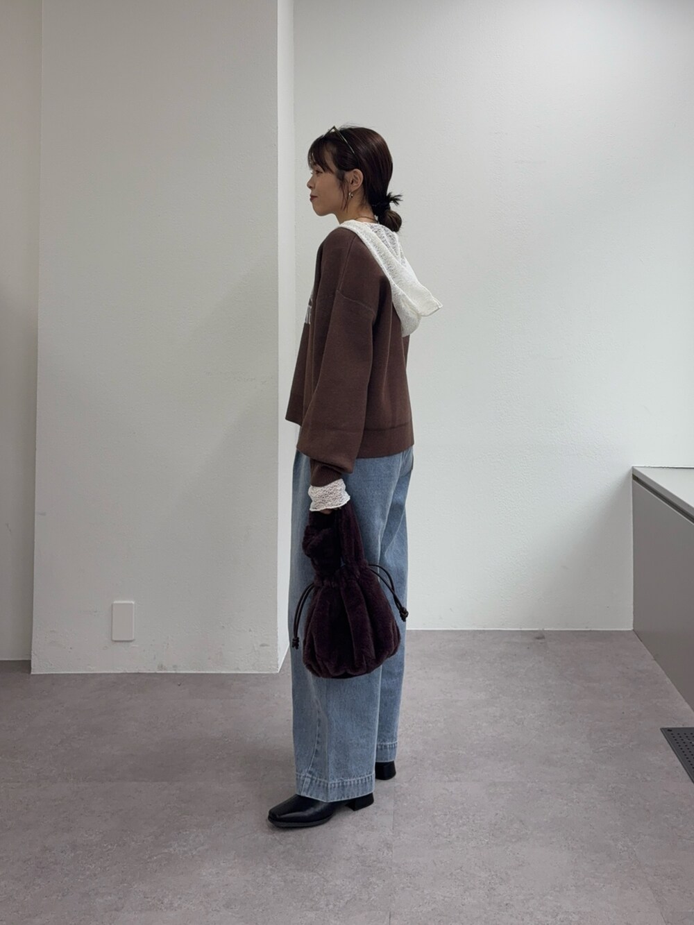 ブラウン系のニット/セーター、ブルー系のデニムパンツ、ブラック系のブーツを着用したレディースの冬コーディネートの2枚目の写真