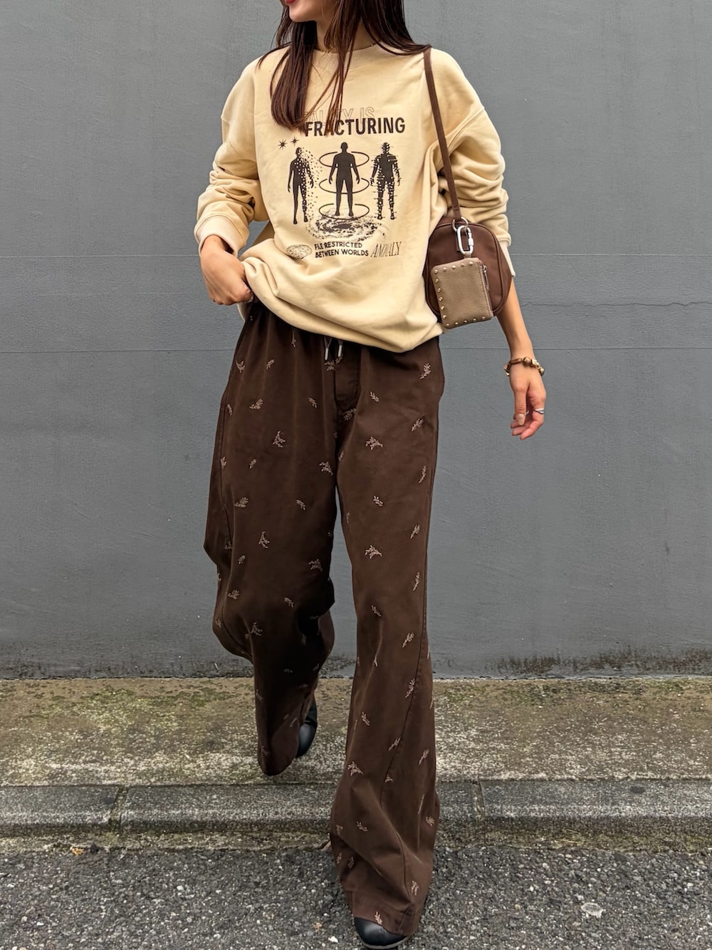 ベージュ系のスウェット、ブラウン系のTシャツ/カットソー、ブラック系のブーツを着用したレディースの秋コーディネートの2枚目の写真