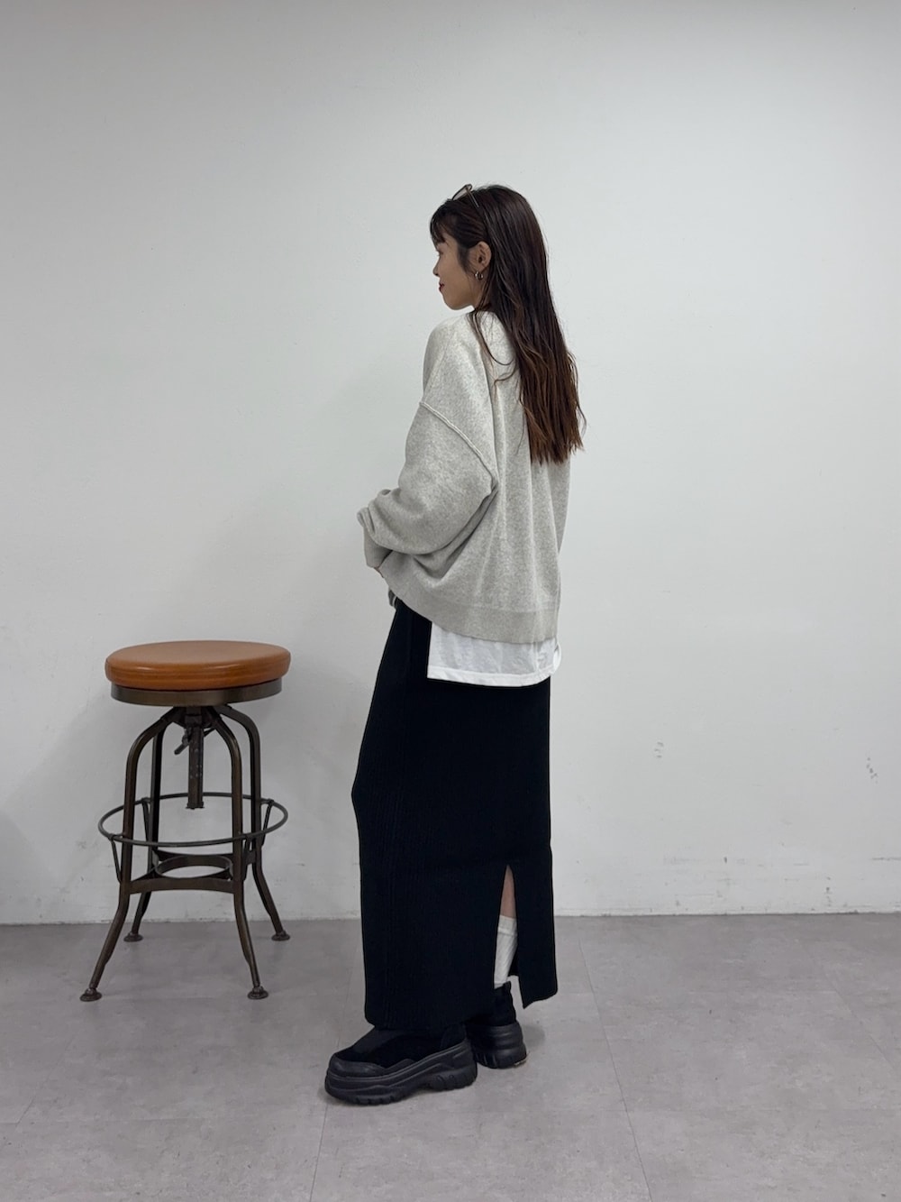 ブラック系のスカート、ブラック系のスニーカー、ホワイト系のニット/セーターを着用したレディースの秋コーディネートの2枚目の写真