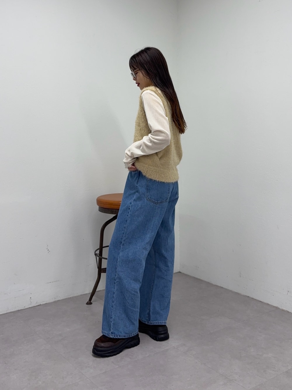 イエロー系のベスト、ブルー系のデニムパンツ、ホワイト系のTシャツ/カットソーを着用したレディースの秋コーディネートの2枚目の写真