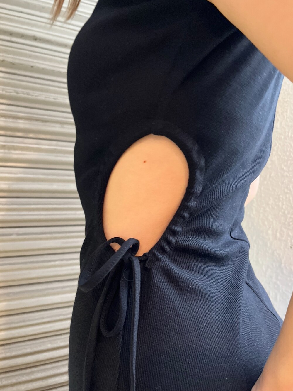 ブラック系のワンピース、ホワイト系のハンドバッグ、ブルー系のサンダルを着用したレディースの夏コーディネートの4枚目の写真