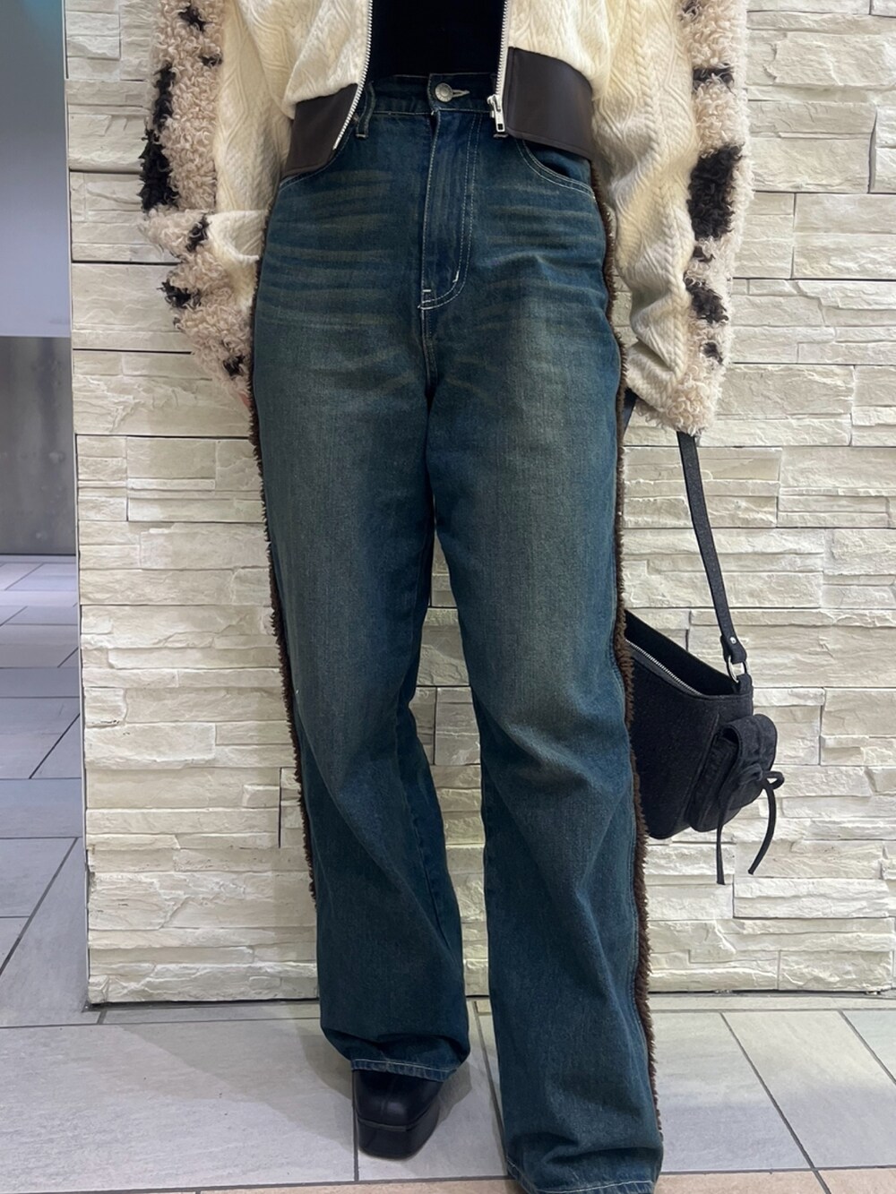 ブラウン系のブルゾン、ブルー系のデニムパンツ、ブラック系のハンドバッグを着用したレディースの秋コーディネートの6枚目の写真