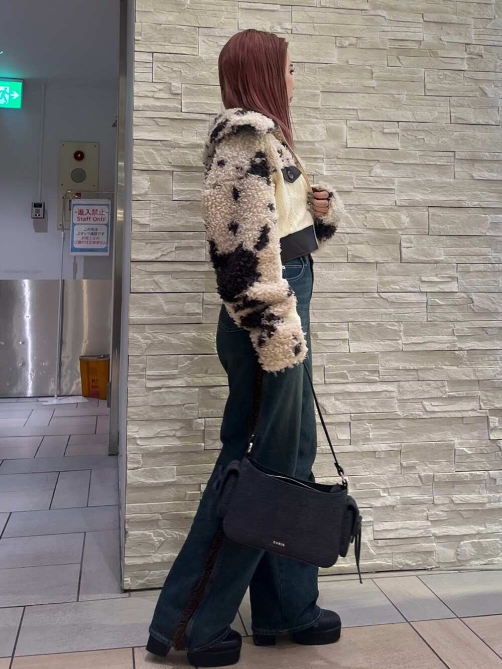 ブラウン系のブルゾン、ブルー系のデニムパンツ、ブラック系のハンドバッグを着用したレディースの秋コーディネートの2枚目の写真