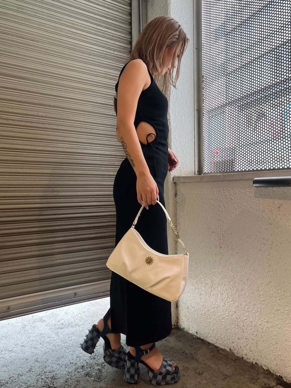 ブラック系のワンピース、ホワイト系のハンドバッグ、ブルー系のサンダルを着用したレディースの夏コーディネートの2枚目の写真