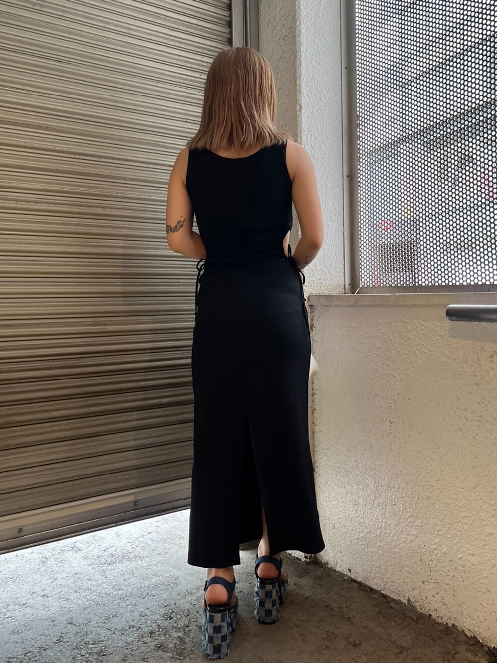 ブラック系のワンピース、ホワイト系のハンドバッグ、ブルー系のサンダルを着用したレディースの夏コーディネートの3枚目の写真