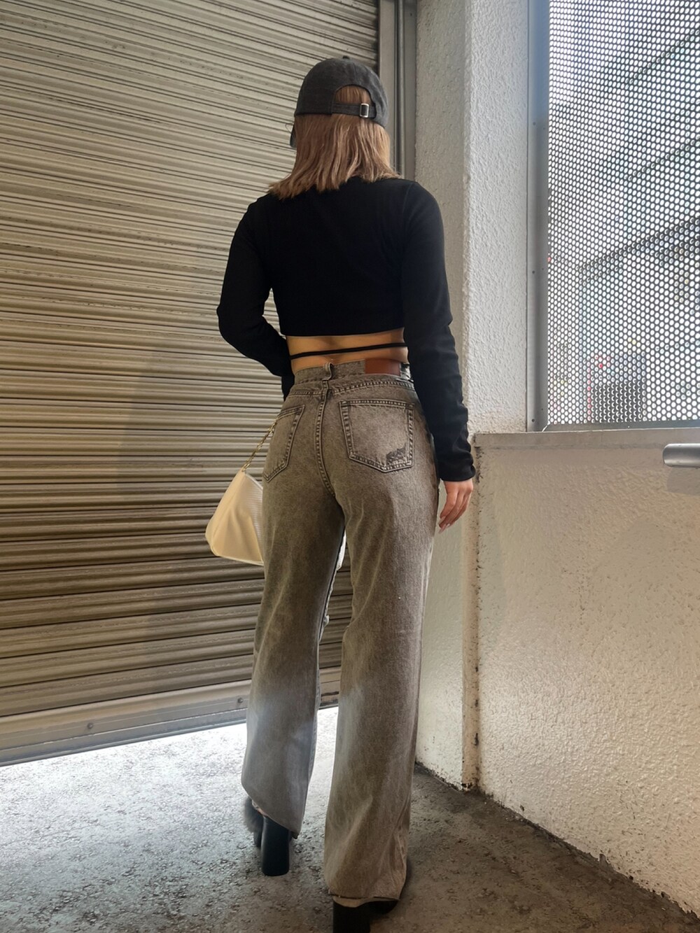 ブラック系のTシャツ/カットソー、ホワイト系のハンドバッグ、ブラック系のサンダルを着用したレディースの夏コーディネートの3枚目の写真