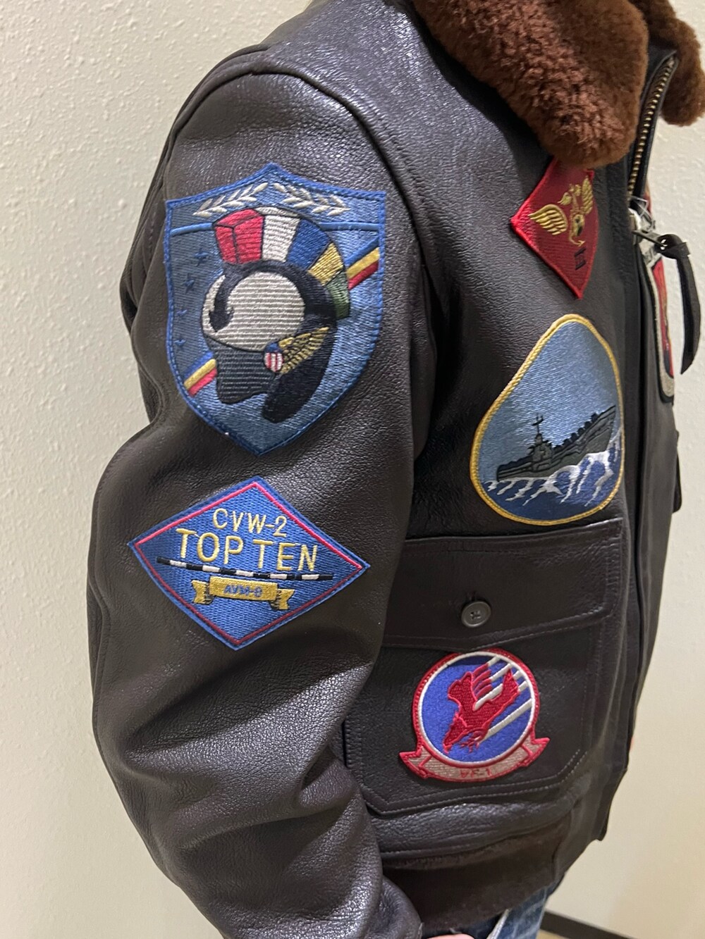 ブラウン系のミリタリージャケット、ホワイト系のTシャツ/カットソー、ブラック系のブーツを着用したメンズの冬コーディネートの5枚目の写真