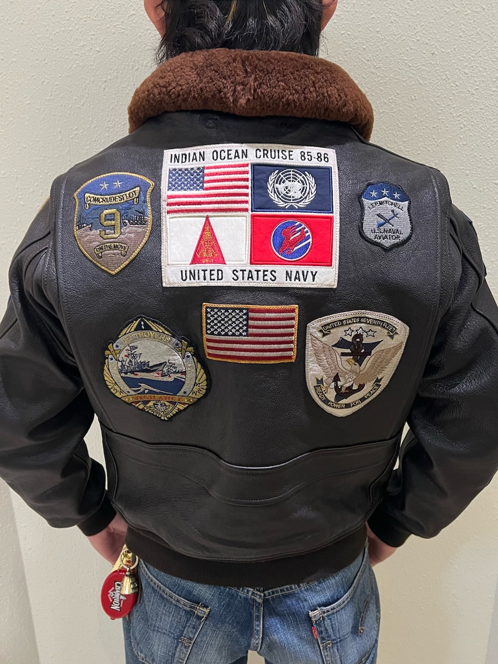 ブラウン系のミリタリージャケット、ホワイト系のTシャツ/カットソー、ブラック系のブーツを着用したメンズの冬コーディネートの3枚目の写真