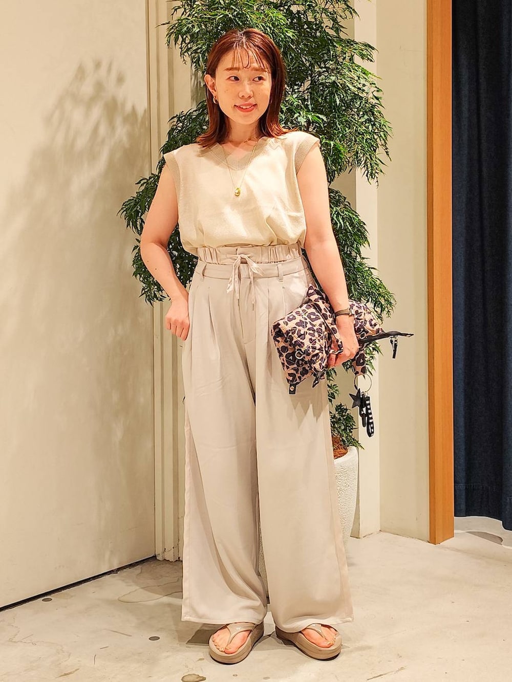 ゴールド系のベスト、ベージュ系のその他パンツ、その他のトートバッグを着用したレディースの夏コーディネートの2枚目の写真