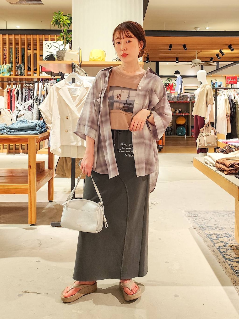 グレー系のシャツ/ブラウス、グレー系のスカート、シルバー系のショルダーバッグを着用したレディースの夏コーディネートの2枚目の写真