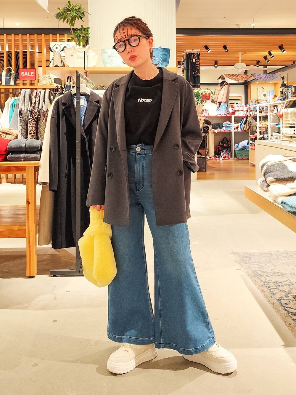 ブルー系のデニムパンツ、イエロー系のハンドバッグ、グレー系のテーラードジャケットを着用したレディースの冬コーディネートの4枚目の写真