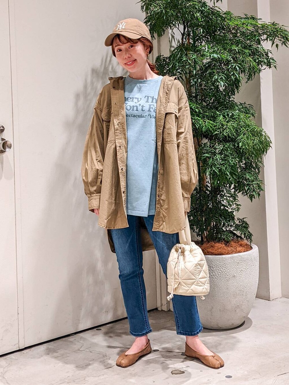 ブルー系のデニムパンツ、ベージュ系のショルダーバッグ、ブルー系のTシャツ/カットソーを着用したレディースの冬コーディネートの2枚目の写真