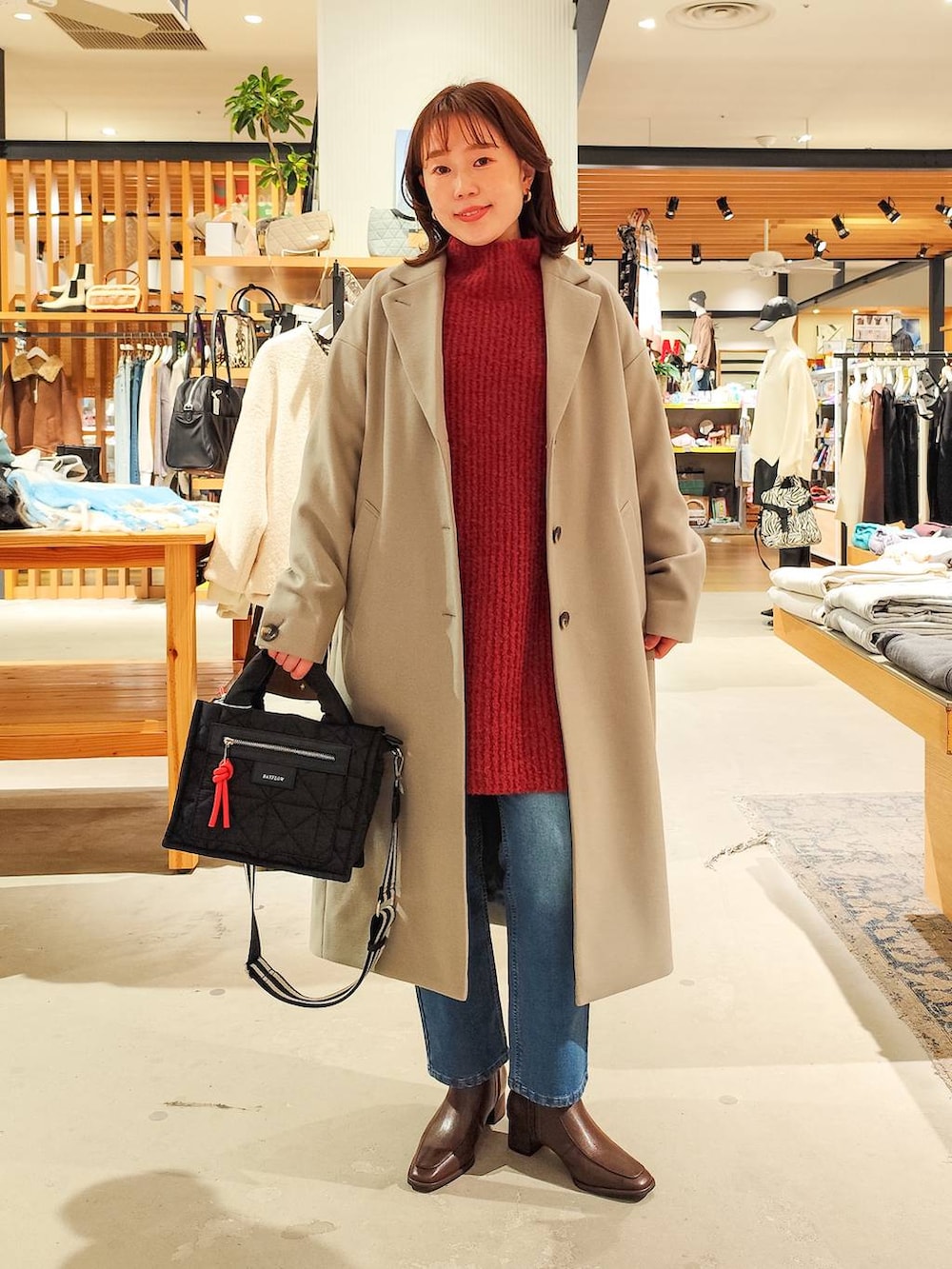 ブラック系のショルダーバッグ、グレー系のチェスターコート、ブルー系のデニムパンツを着用したレディースの冬コーディネートの2枚目の写真