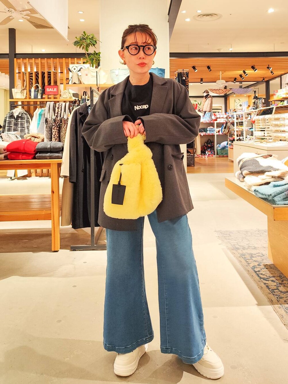 ブルー系のデニムパンツ、イエロー系のハンドバッグ、グレー系のテーラードジャケットを着用したレディースの冬コーディネートの2枚目の写真