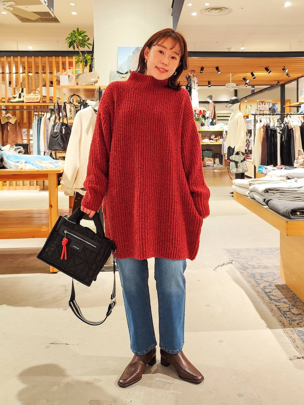 ブラック系のショルダーバッグ、グレー系のチェスターコート、ブルー系のデニムパンツを着用したレディースの冬コーディネートの6枚目の写真