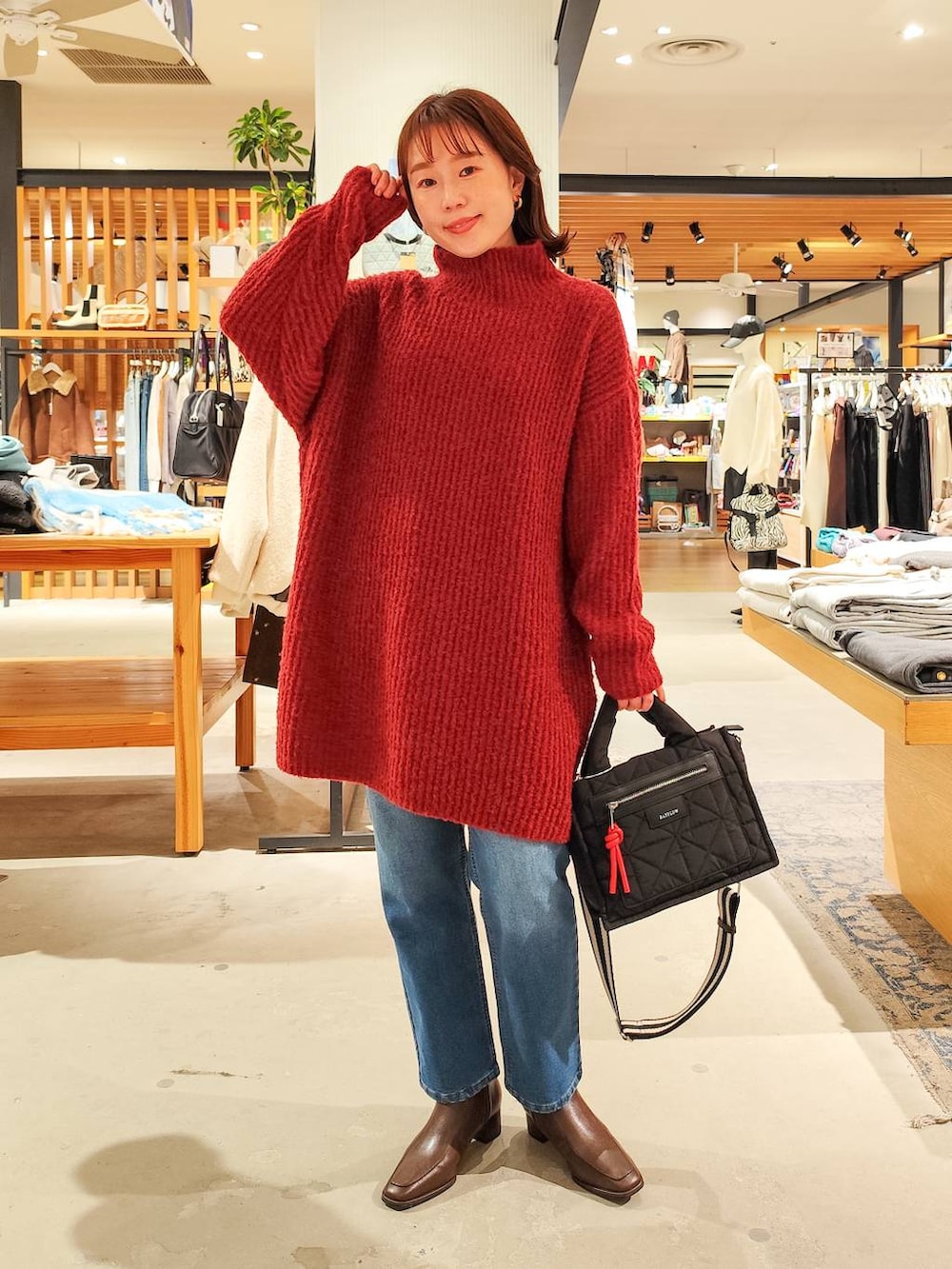 ブラック系のショルダーバッグ、グレー系のチェスターコート、ブルー系のデニムパンツを着用したレディースの冬コーディネートの3枚目の写真