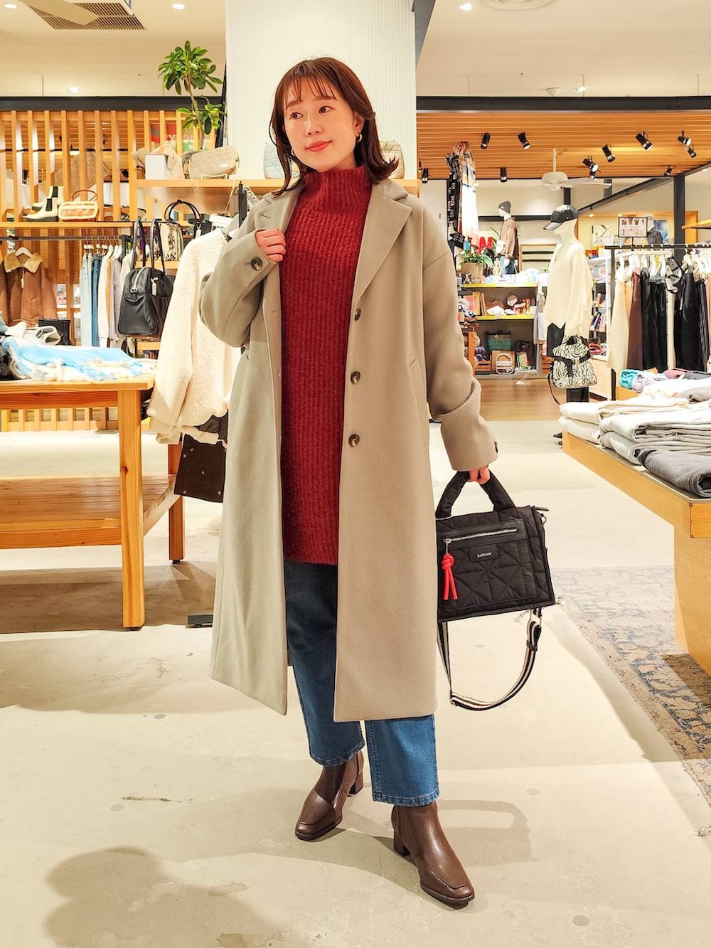 ブラック系のショルダーバッグ、グレー系のチェスターコート、ブルー系のデニムパンツを着用したレディースの冬コーディネートの4枚目の写真