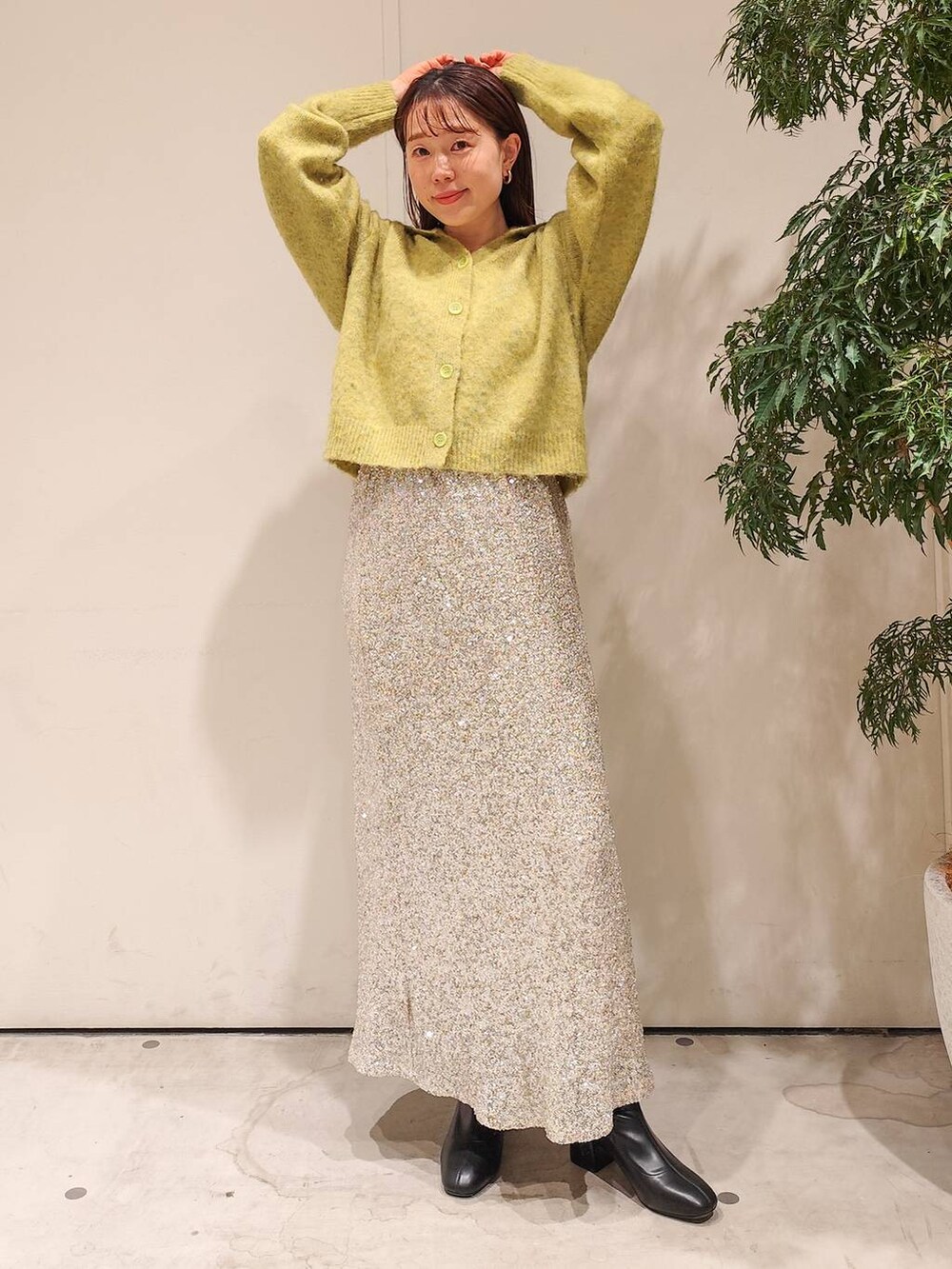 ブラック系のブーツ、ベージュ系のスカート、イエロー系のニット/セーターを着用したレディースの秋コーディネートの2枚目の写真