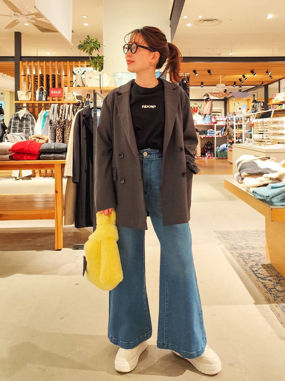 ブルー系のデニムパンツ、イエロー系のハンドバッグ、グレー系のテーラードジャケットを着用したレディースの冬コーディネートの3枚目の写真