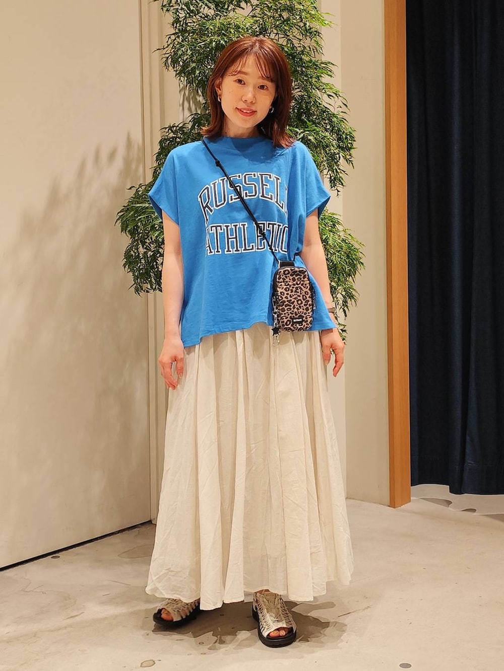 ベージュ系のスカート、ブラウン系のショルダーバッグ、ブルー系のTシャツ/カットソーを着用したレディースの夏コーディネートの2枚目の写真